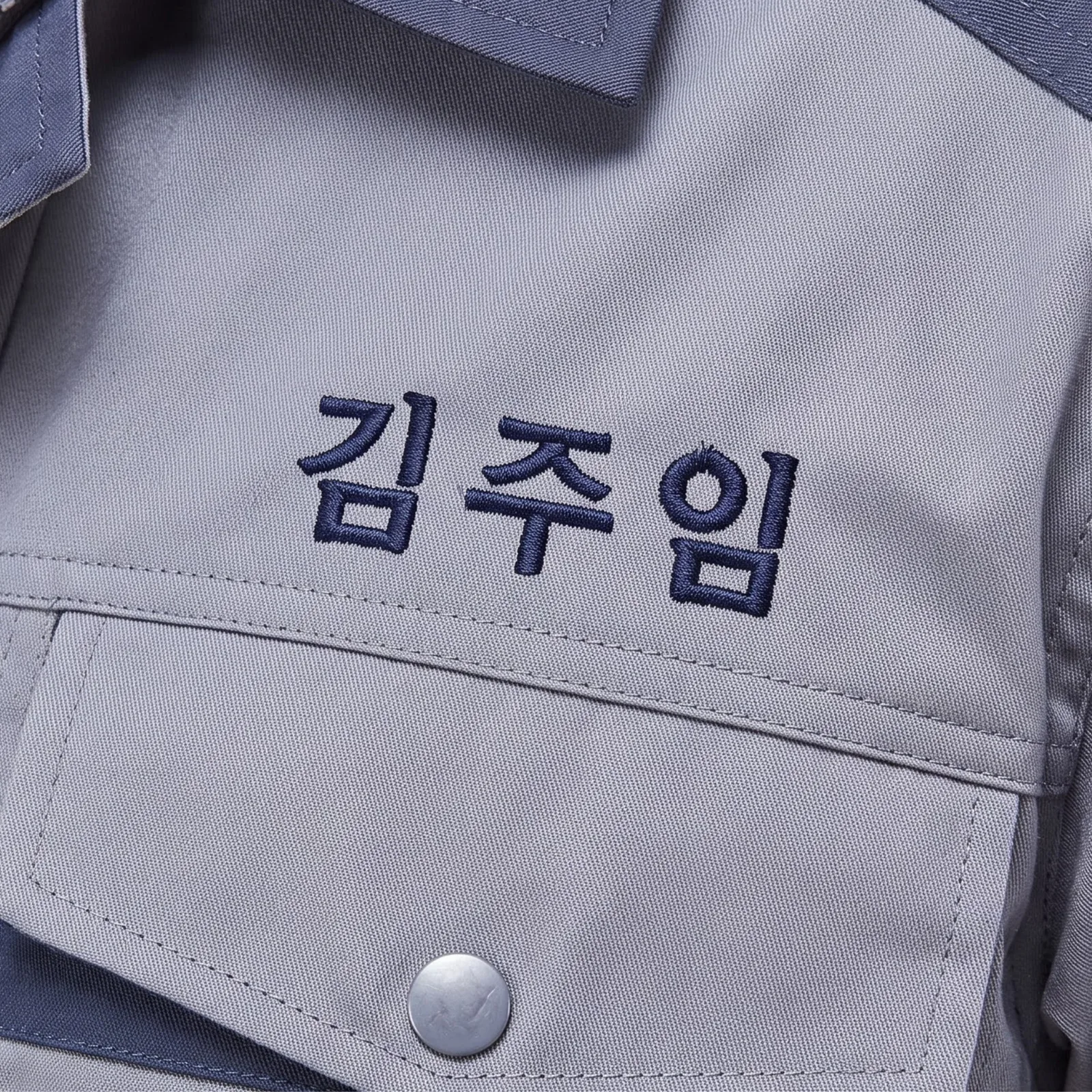 회색 작업복에 남색 자수로 새긴 김주임 명찰